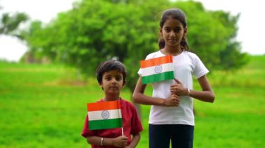 Sevimli küçük Hintli çocuklar el sallıyor ya da arka planda yeşillik ile koşuyorlar Bağımsızlık Günü 'nü ya da Cumhuriyet Günü' nü kutluyorlar.