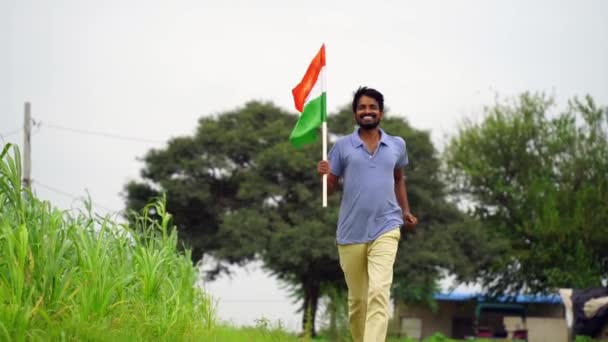 インドの若者は バックグラウンドで緑とトリコロールを保持 振ったり走ったり 独立または共和国の日を祝います — ストック動画