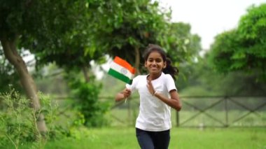 Sevimli küçük Hintli çocuklar el sallıyor ya da arka planda yeşillik ile koşuyorlar Bağımsızlık Günü 'nü ya da Cumhuriyet Günü' nü kutluyorlar.