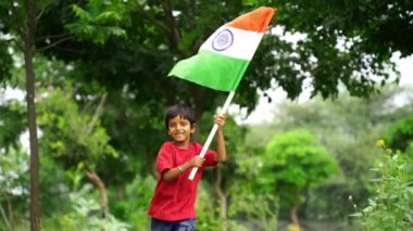 Sevimli küçük Hintli çocuklar el sallıyor ya da arka planda yeşillik ile koşuyorlar Bağımsızlık Günü 'nü ya da Cumhuriyet Günü' nü kutluyorlar.