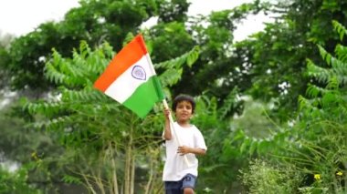 Sevimli küçük Hintli çocuklar el sallıyor ya da arka planda yeşillik ile koşuyorlar Bağımsızlık Günü 'nü ya da Cumhuriyet Günü' nü kutluyorlar.