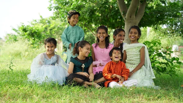 Indian brothers and sisters celebrating Raksha Bandhan or Rakhi festival at garden while wearing traditional cloths and sitting over nature background