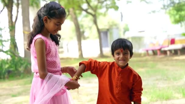 穿着连衣裙的可爱的印度姑娘为手上的弟弟绑上了手镯 — 图库视频影像