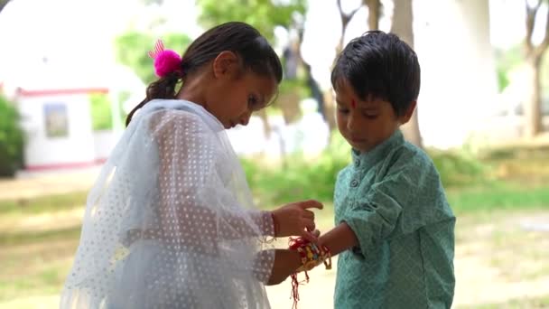 穿着连衣裙的可爱的印度姑娘为手上的弟弟绑上了手镯 — 图库视频影像