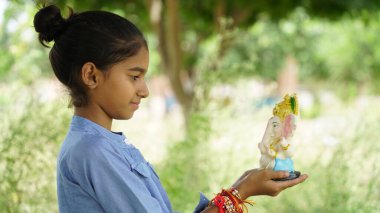 Ganesha ve dua eden küçük Hintli kız çocuğu, Hint Ganesh festivali ya da Diwali festivali