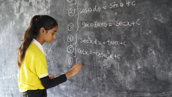 Happy Indian school girl child standing  in front of black chalkboard background. Education Concept or Back to School