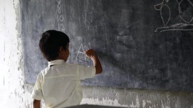 Asyalı okul çocuğu üniforma giyiyor. Okul üniformalı küçük, mutlu Hintli çocuk portresi, siyah tahta gösteren sevimli ilkokul çocuğu. Çocuk eğitimi konsepti. kırsal Hindistan.