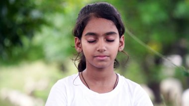 Sevimli küçük kız bahçede yoga meditasyonu yapıyor. Küçük Hintli kız meditasyon yapıyor.