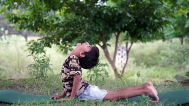 Yakışıklı küçük çocuk bahçede yoga meditasyonu yapıyor. Küçük Hintli çocuk meditasyon yapıyor.