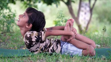Dışarıda yoga yapan muhteşem bir çocuğun portresi. Güzel bir çocuk yoga yapıyor ya da jimnastik yapıyor. Nilüfer pozisyonunda meditasyon yapan küçük çocuklar