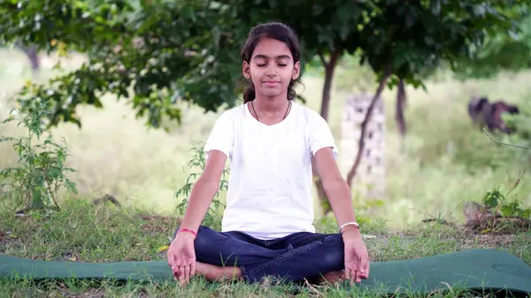 ガーデンで真剣なヨガの瞑想をしている少女を魅了する 瞑想をしている小さなインドの少女 — ストック写真