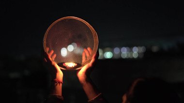 Karva Chauth, Hindu kadınların kocalarının güvenliği ve uzun ömürlülüğü için kutladıkları bir günlük festival. Hintli kadın, eleğe bakıyor, Karwa Chauth 'u kutluyor.