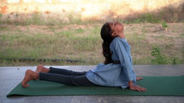 Sevimli küçük kız bahçede yoga meditasyonu yapıyor. Küçük Hintli kız meditasyon yapıyor.