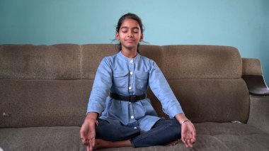 Sevimli küçük kız bahçede yoga meditasyonu yapıyor. Küçük Hintli kız meditasyon yapıyor.