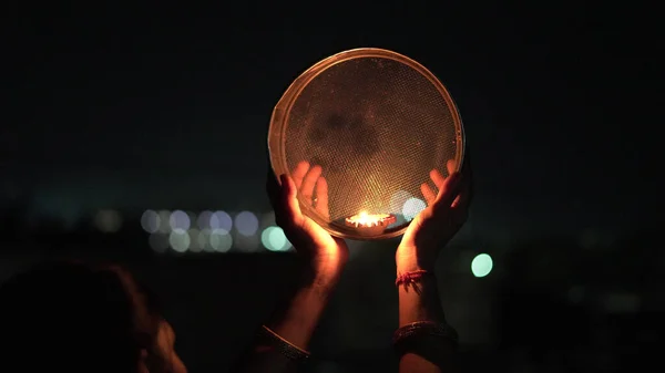 Young Indian woman celebrating Karva Chauth at night. Karva Chauth is a one-day festival celebrated by Hindu women four days after purnima (a full moon) in the month of Kartika.
