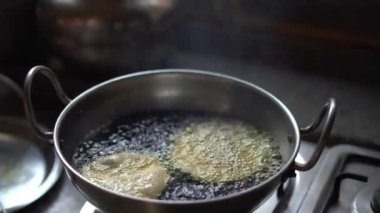 Kochuriler kızartma tavasında kızartılıyor. Kochuri, Kachauri 'nin kachori' si baharatlı bir çerez, kızarmış hamur köftesi ve Hindistan 'da çok popüler bir sokak yiyeceğidir..
