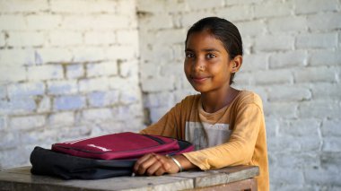 Mutlu Hintli ilkokul öğrencileri sınıfta masalarında oturup kalemle, sınavla, kadın eğitim konseptiyle not defterine yazıyorlar..