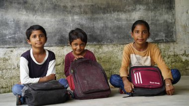 Mutlu Hintli ilkokul öğrencileri sınıfta masalarında oturup kalemle, sınavla, kadın eğitim konseptiyle not defterine yazıyorlar..