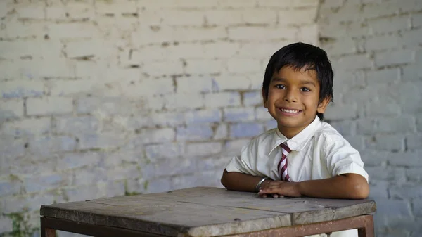 Portrait of happy indian school child sitting at desk in classroom, school kids with pens and notebooks writing test Elementary school, Education concept.