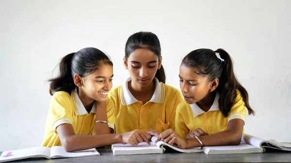 快乐的印度小学女生坐在课桌前 用铅笔 女性教育理念等笔记本写作 免版税图库图片