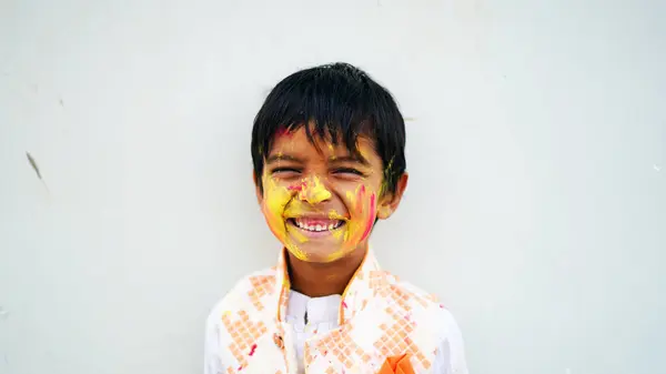 Happy Indian kids playing colours, smiling with colors on face or asian children celebrating Holi. Concept for Indian festival Holi. Bright kids smeared in colored powder
