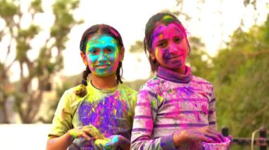 Holi 'yi kutlayan Asyalı çocuklara gülümseyen mutlu Hintli bir kızın görüntüsü.