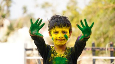 Mutlu şirin, gülümseyen küçük Hintli çocuklar renkli ellerini ya da avuç içini gösteriyorlar ya da renkli Holi festivali oynuyorlar.