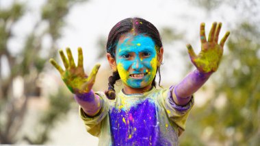 Mutlu şirin, gülümseyen küçük Hintli çocuklar renkli ellerini ya da avuç içini gösteriyorlar ya da renkli Holi festivali oynuyorlar.