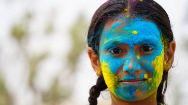 Holi festivali kutlaması sırasında renkli elleri kameraya gösteren uygulamalı holi rengi pudralı küçük sevimli kız çocuğu.