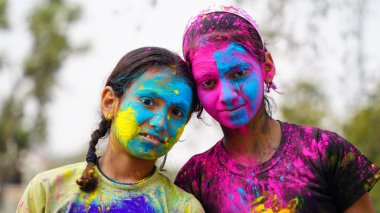 Holi festivali kutlaması sırasında renkli elleri kameraya gösteren uygulamalı holi rengi pudralı küçük sevimli kız çocuğu.