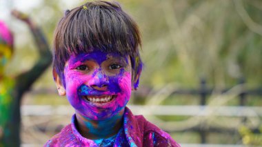 Mutlu Hintli arkadaşlar ya da çocuklar Hindu Holi festivalini kutlarken birbirlerine renk uygulayarak, en iyi arkadaşlar. Gulal 'ın farklı tonlarında tabağı tutan dişi kardeşler.