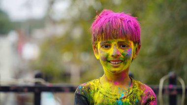 Mutlu şirin, gülümseyen küçük Hintli çocuklar renkli ellerini ya da avuç içini gösteriyorlar ya da renkli Holi festivali oynuyorlar.