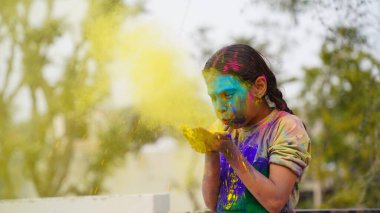Mutlu Hintli arkadaşlar ya da çocuklar Hindu Holi festivalini kutlarken birbirlerine renk uygulayarak, en iyi arkadaşlar. Gulal 'ın farklı tonlarında tabağı tutan dişi kardeşler.