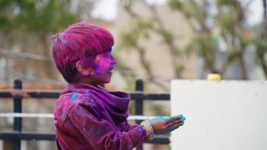 Holi Festivali sırasında çocuklar renkli tozla kaplıydı. Mutlu Asyalı çocuklar Hint Holi festivalini yüzlerinde renkli boya tozuyla kutluyorlar.
