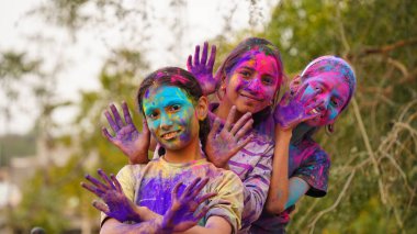 Mutlu şirin, gülümseyen küçük Hintli çocuklar renkli ellerini ya da avuç içini gösteriyorlar ya da renkli Holi festivali oynuyorlar.