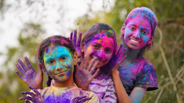 Mutlu şirin, gülümseyen küçük Hintli çocuklar renkli ellerini ya da avuç içini gösteriyorlar ya da renkli Holi festivali oynuyorlar.