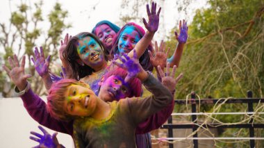 Mutlu şirin, gülümseyen küçük Hintli çocuklar renkli ellerini ya da avuç içini gösteriyorlar ya da renkli Holi festivali oynuyorlar.