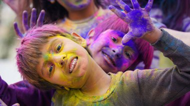 Holi Festivali sırasında çocuklar renkli tozla kaplıydı. Mutlu Asyalı çocuklar Hint Holi festivalini yüzlerinde renkli boya tozuyla kutluyorlar.