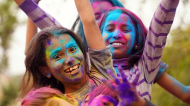 Holi festivali kutlamalarında renkli elleri kameraya gösteren uygulamalı holi rengi pudralı küçük sevimli çocuklar.