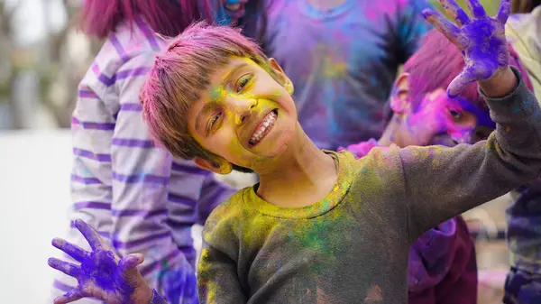 Kid blowing holi colour powder from hand during Holi festival celebration - Concept of young kids having fun by playing holi during festive