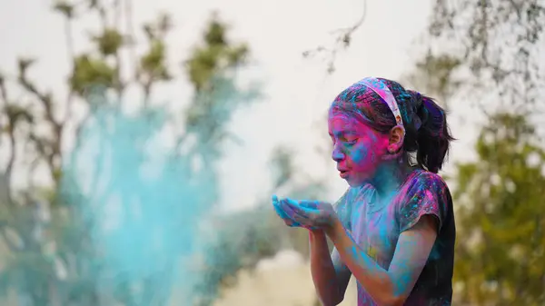 ホリ祭りのお祝いの間にカメラにカラフルな手を示す適用ホリ色の粉を持つ若いかわいい陽気な女の子の子供 ストックフォト