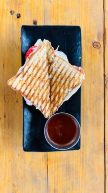 Ot, soğan, domates, peynir ve biberli lezzetli vejetaryen sandviçi ahşap masada kırmızı sosla servis ediliyor.