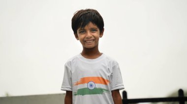 Küçük çocuk selam veriyor, üç renkli Hint bayrağı tişörtü giyiyor ve yüzü Hint bayrağı renkleriyle boyanmış. Bağımsızlık Günü Kutlaması mı Cumhuriyet Günü mü?.