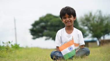 Beyaz ırktan yakışıklı küçük bir Hintli çocuk ya da çocuk Hindistan ulusal bayrağından ayakta duran ve vatanseverlik gösteren bir bebek giyer. Har Ghar Tiranga