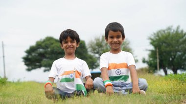 Üç renkli Hint tişörtü giyen, yüzü üç renkli boyayla boyanmış ve selam veren küçük bir çocuk. Bağımsızlık Günü ya da Cumhuriyet Günü 'nü kutluyoruz. Har Ghar Tiranga