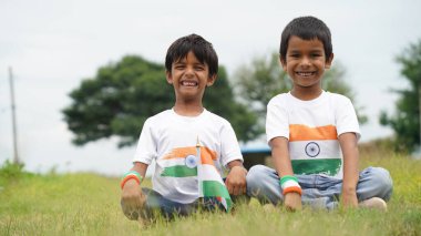 Mutlu Hindistan Sevimli Gülümseyen küçük çocuk dışarıda parka üç renkli bayrak sallayarak Bağımsızlık Günü 'nü veya Cumhuriyet Günü' nü kutluyor..