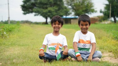Mutlu Hindistan Sevimli Gülümseyen küçük çocuk dışarıda parka üç renkli bayrak sallayarak Bağımsızlık Günü 'nü veya Cumhuriyet Günü' nü kutluyor..