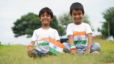 Beyaz ırktan yakışıklı küçük bir Hintli çocuk ya da çocuk Hindistan ulusal bayrağından ayakta duran ve vatanseverlik gösteren bir bebek giyer. Har Ghar Tiranga