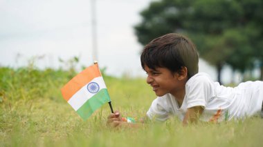 Beyaz ırktan yakışıklı küçük bir Hintli çocuk ya da çocuk Hindistan ulusal bayrağından ayakta duran ve vatanseverlik gösteren bir bebek giyer. Har Ghar Tiranga