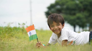 Üç renkli Hint tişörtü giyen, yüzü üç renkli boyayla boyanmış ve selam veren küçük bir çocuk. Bağımsızlık Günü ya da Cumhuriyet Günü 'nü kutluyoruz. Har Ghar Tiranga